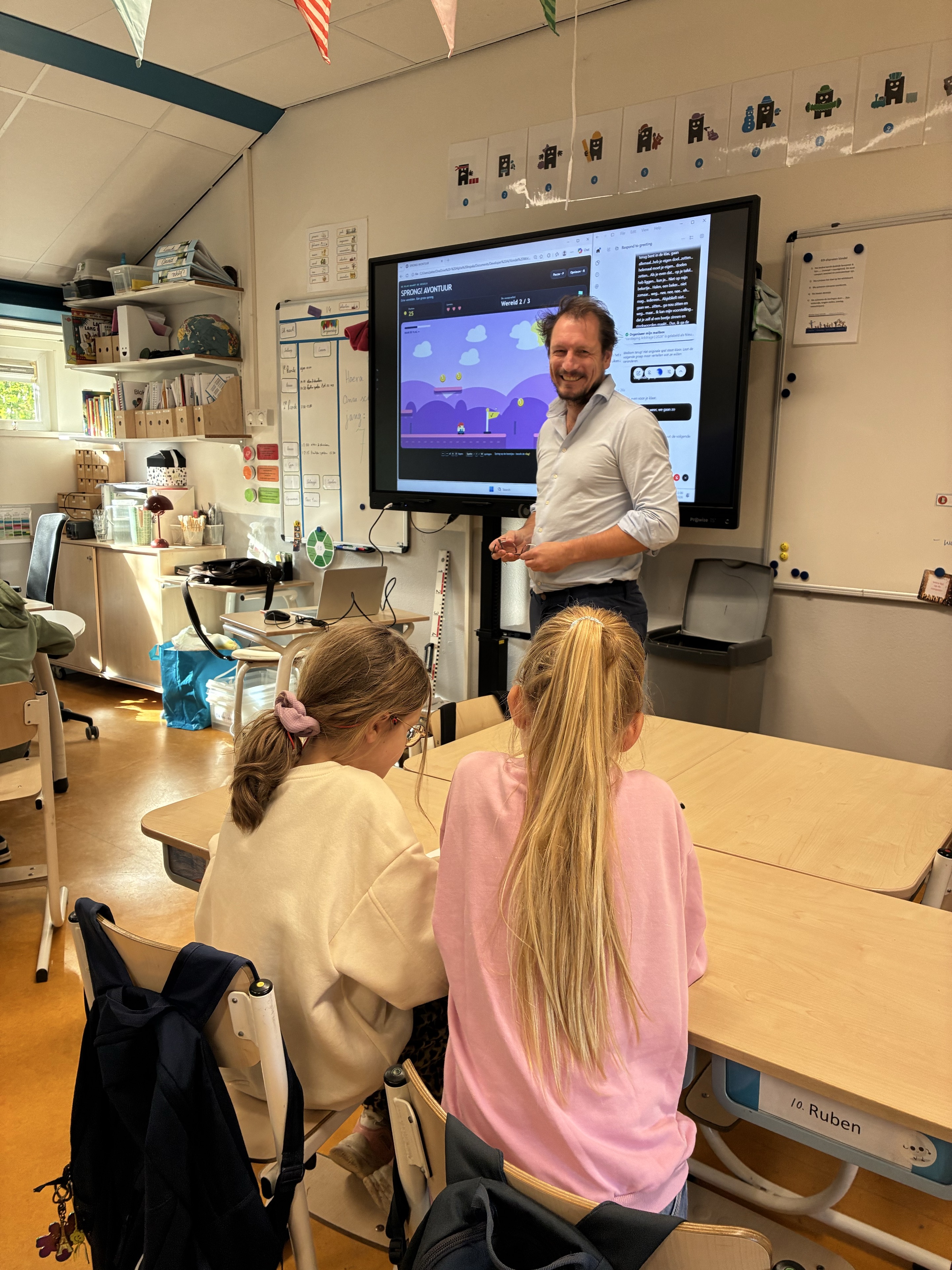 Peter begeleidt een workshop in een klaslokaal, met een platformspel op het digibord.